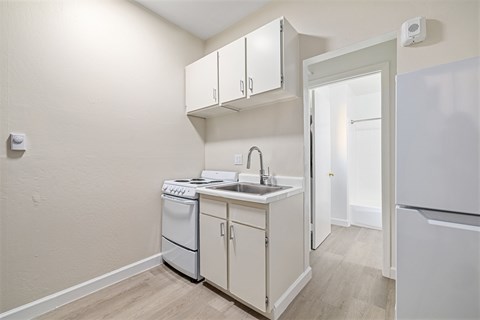 A small kitchen with a sink, stove and refrigerator.
