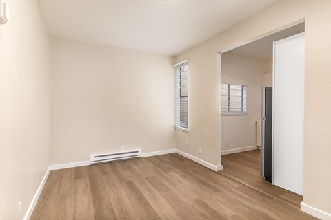 A room with wooden flooring and a window with blinds.