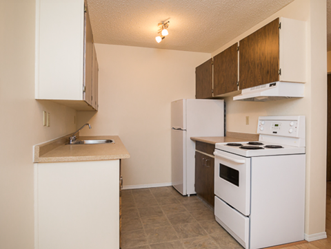 A kitchen with white appliances and wooden cabinets.