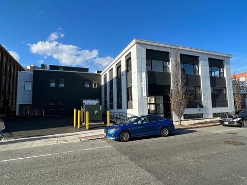 A blue car is parked in front of a white building.