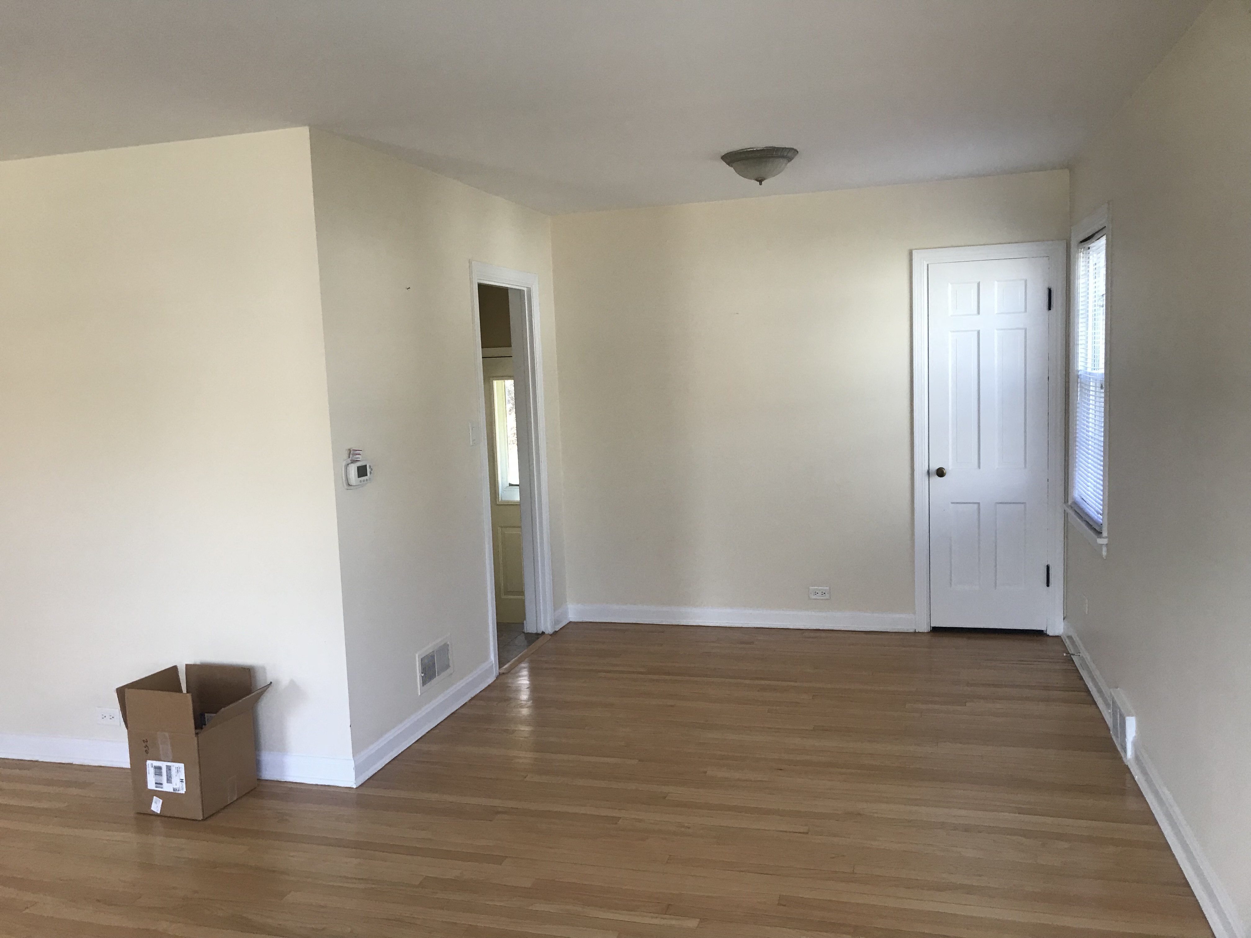 A room with a wooden floor and a cardboard box on it.