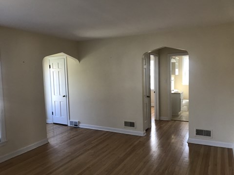 A room with a white door and wooden floors.