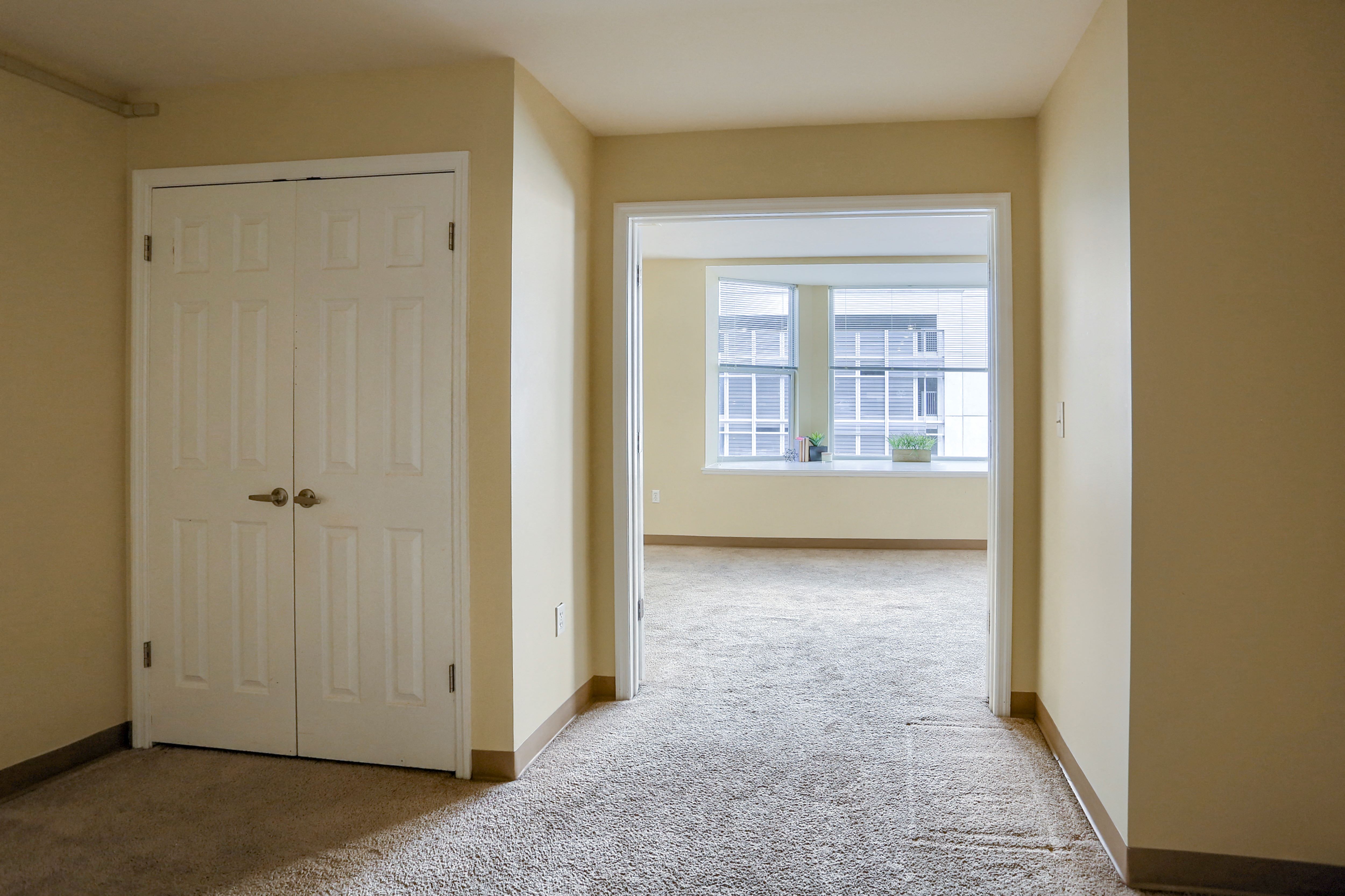an empty room with a white door and a window