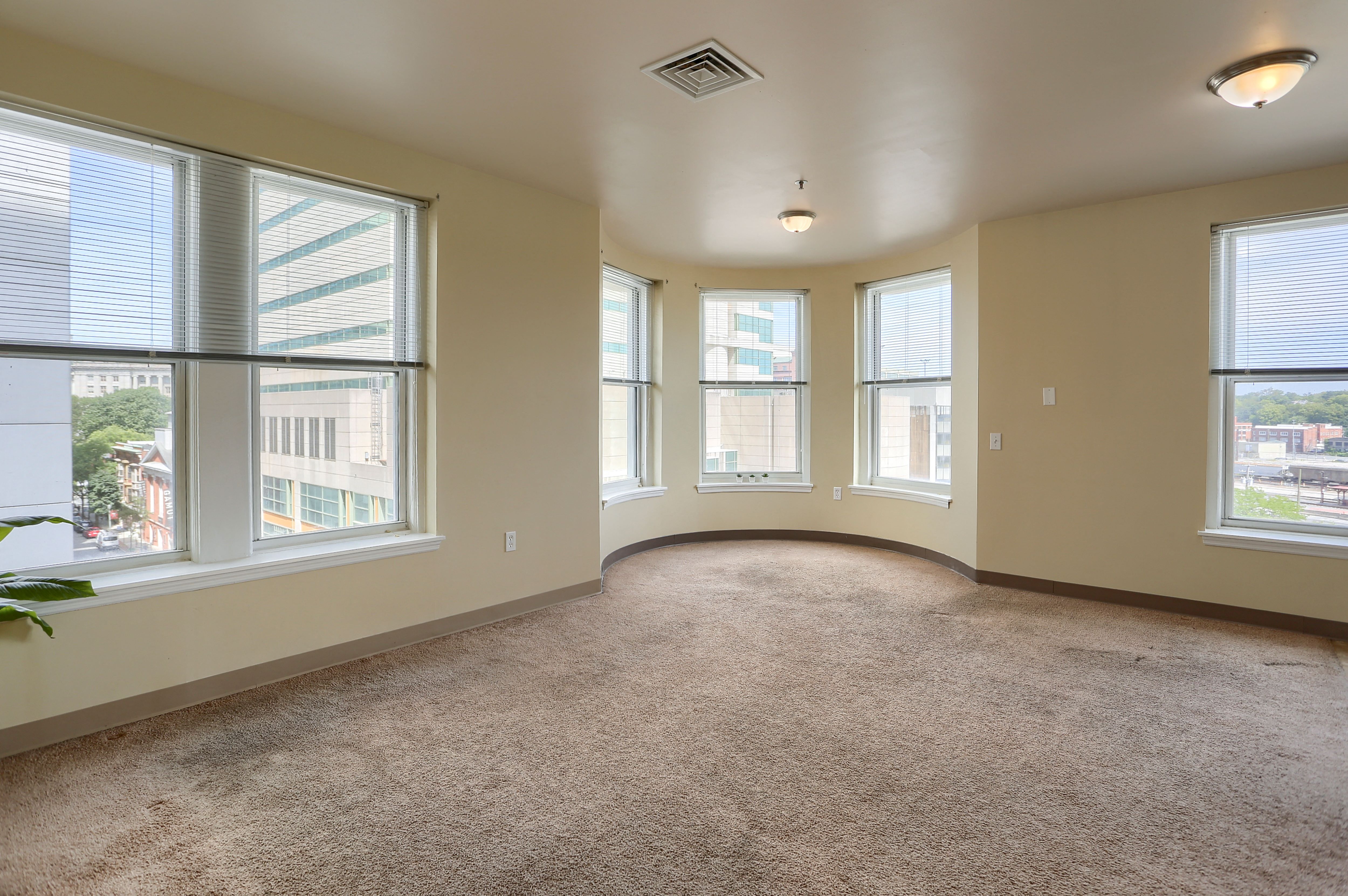 an empty living room with large windows and a carpeted floor