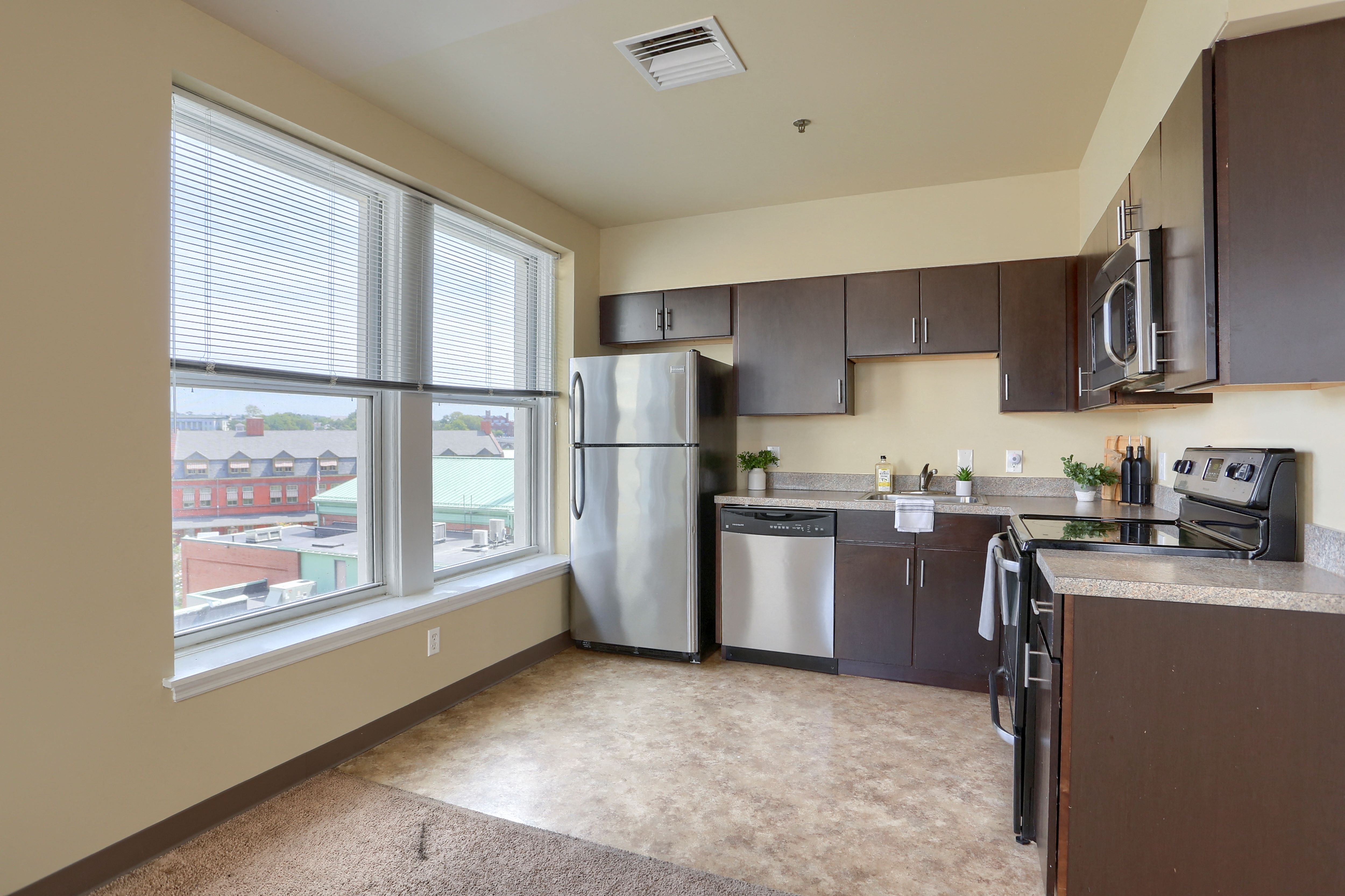 an empty kitchen with stainless steel appliances and a large window