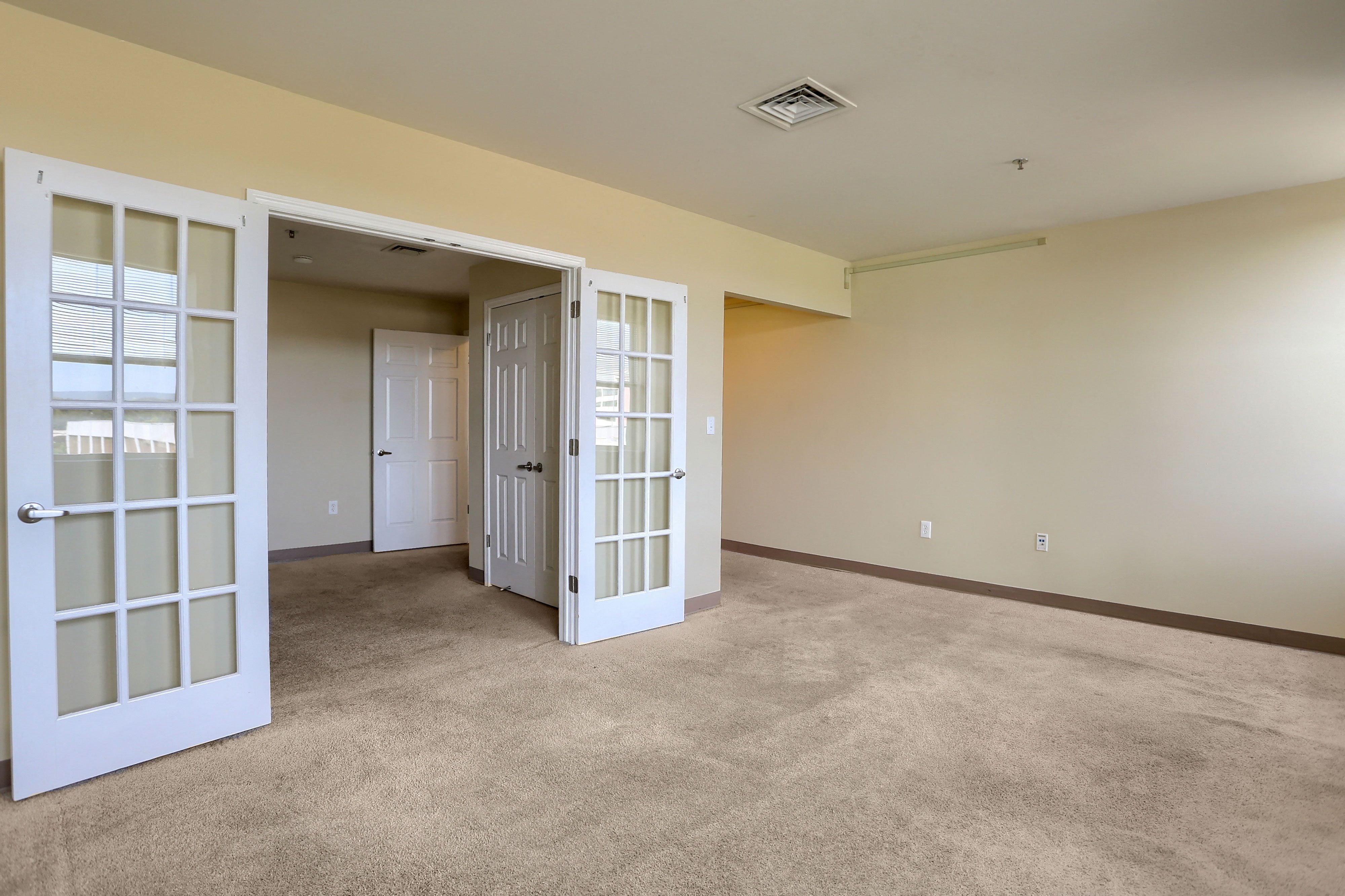 an empty living room doors and a door to a bedroom