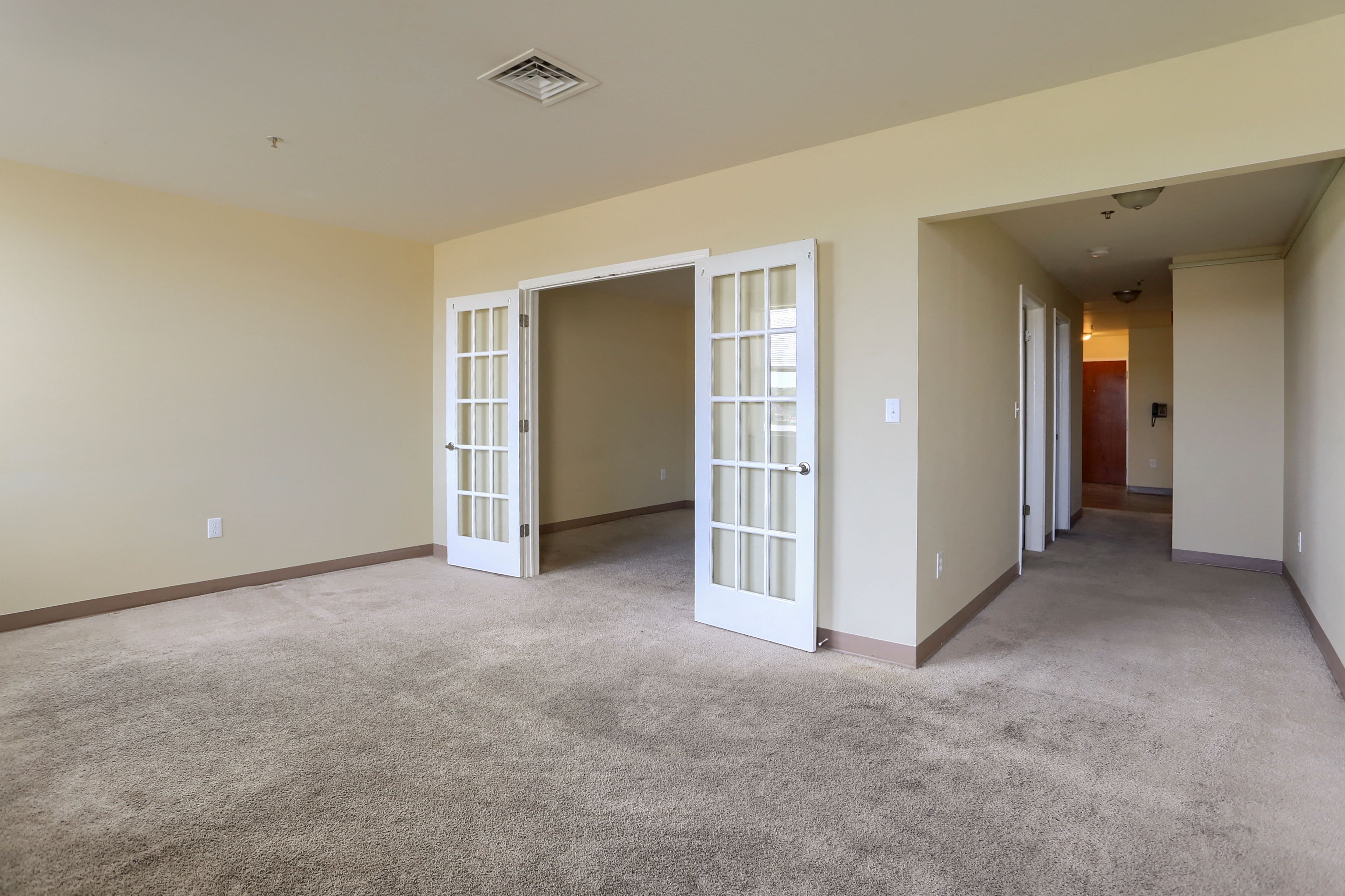an empty living room with open doors to a hallway
