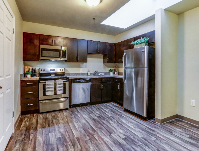 an empty kitchen with stainless steel appliances and wooden floors