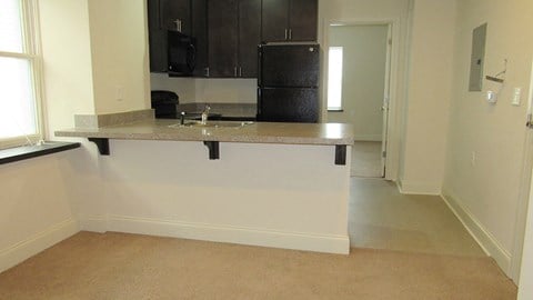 a kitchen with a counter and a black refrigerator