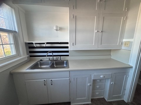 A kitchen with white cabinets and a striped backsplash.