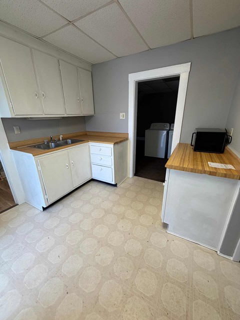 A kitchen with white appliances and a wooden counter.