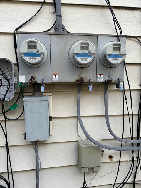 Three electricity meters are installed on a house's exterior wall.