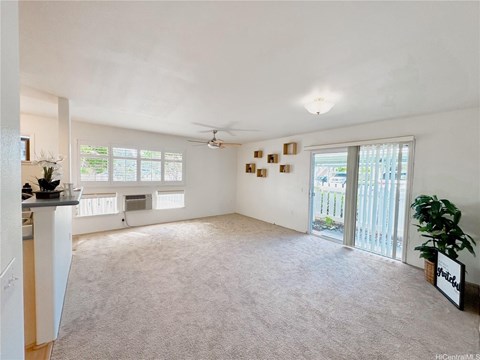 A spacious living room with a ceiling fan and sliding glass doors.