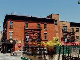 a red brick building with fire escapes on a city street