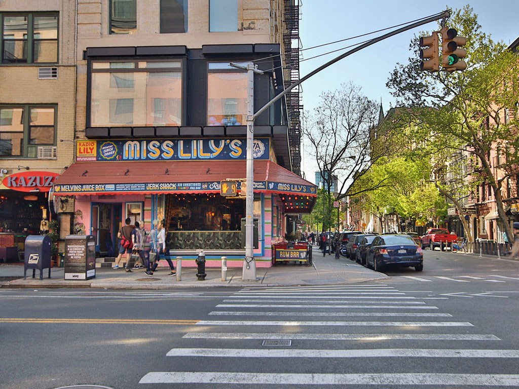 a busy city street with pedestrians and a restaurant on the corner