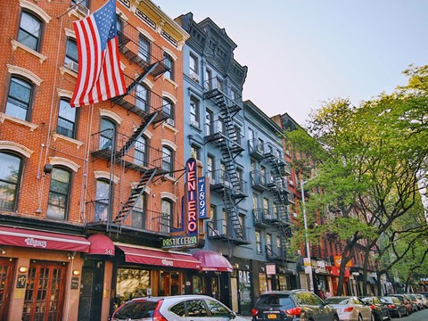 a city street with buildings and cars and an flag
