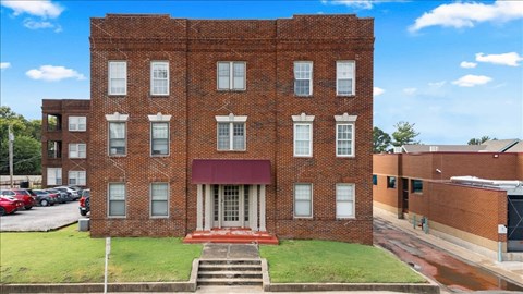 A red brick building with a red awning and a set of stairs leading up to the entrance.