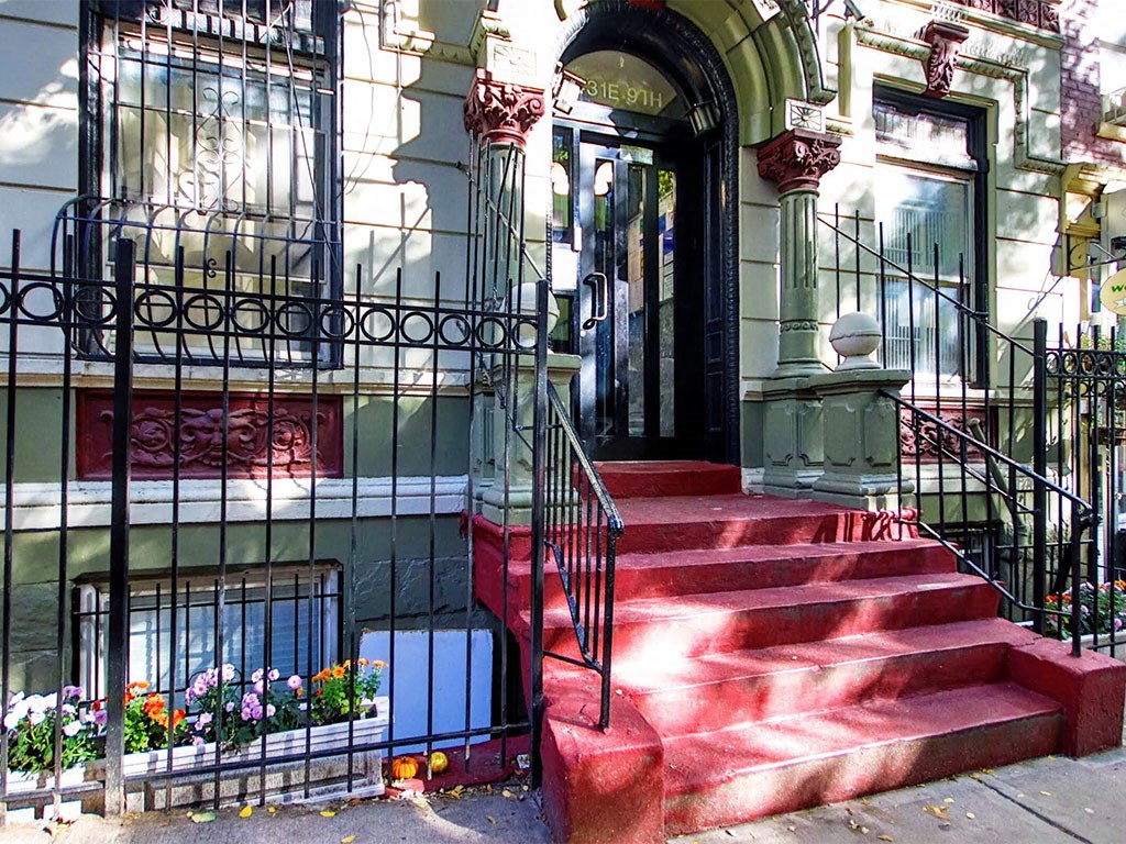 a house with red steps and a black fence and a door