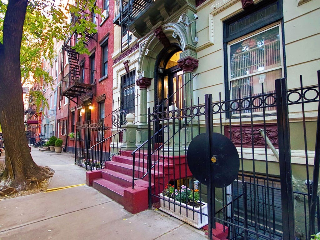 a city street with red brick steps and a wrought iron fence