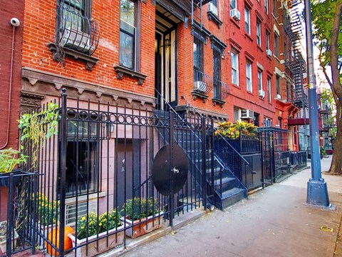 A red brick building with a black iron fence in front.