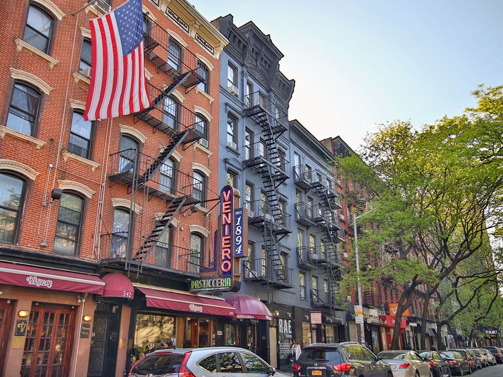 a row of buildings on a city street with an flag