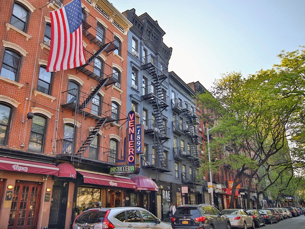 a city street with cars and a flag on a building