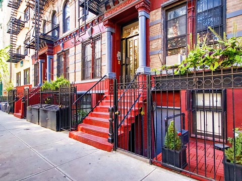 a red house with red steps and a black fence