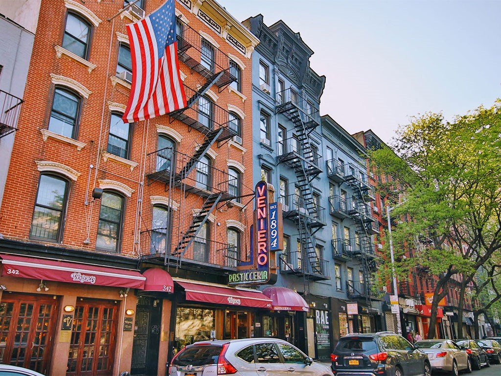 a city street with cars and a flag on a building