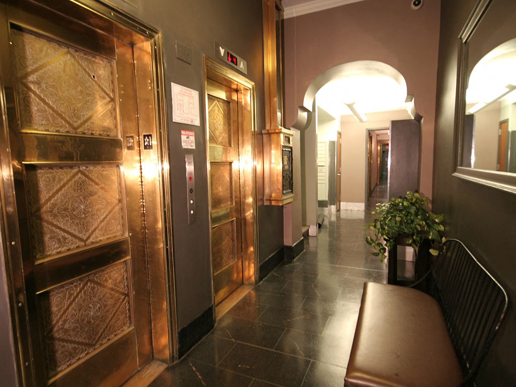 the lobby of a building with wooden doors and a bench
