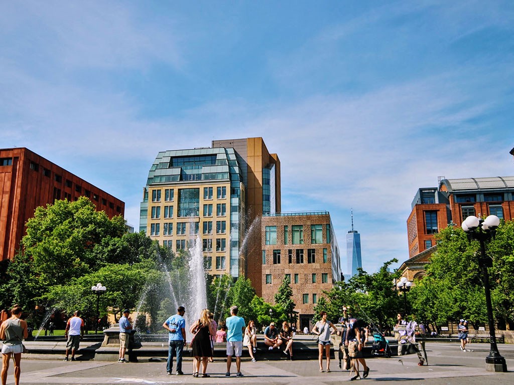 people standing around a fountain in a city square