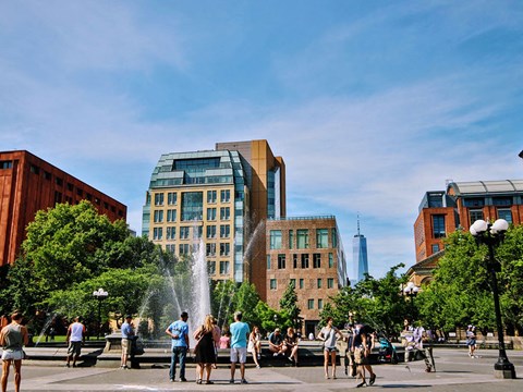 people standing around a fountain in a city square