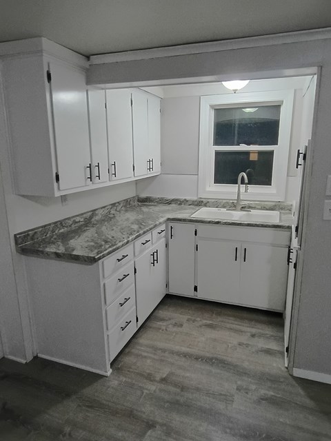 A kitchen with white cabinets and a marble countertop.