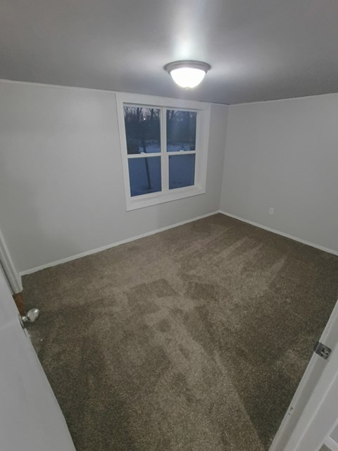 A room with a carpeted floor and a window showing a snowy scene outside.