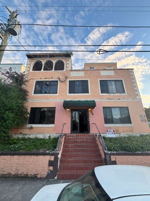 A pink building with a green awning and a sign that says "FOR SALE".