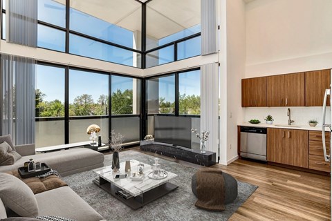 A modern living room with a glass coffee table and a grey sofa.