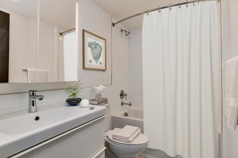 A white bathroom with a toilet, sink, and shower.
