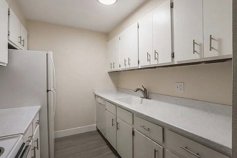 A kitchen with white cabinets and a white refrigerator.