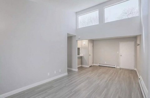 A spacious room with wooden flooring and white walls.