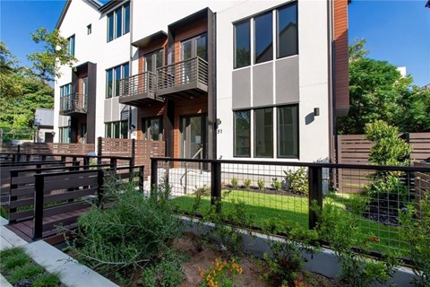 A modern apartment building with a balcony and a fence.