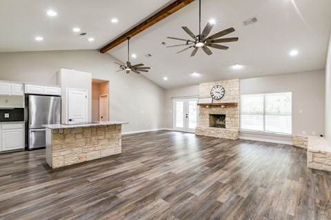 A spacious living room with wood flooring and a stone fireplace.