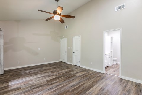 A room with a ceiling fan and wood flooring.