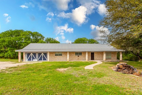 A house with a grey roof and a stone wall in front.