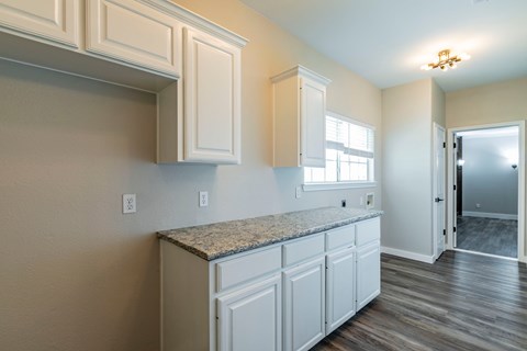 A kitchen with white cabinets and a granite countertop.