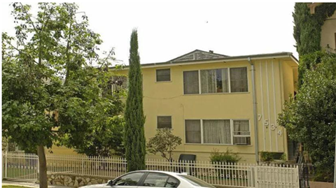 A yellow house with a white car parked in front.