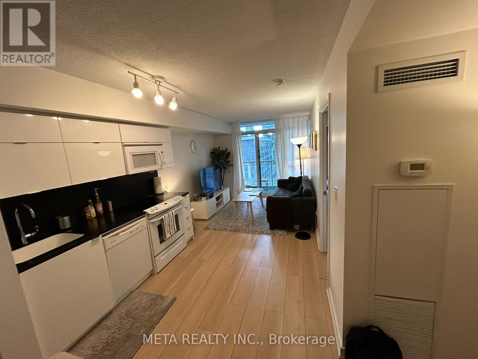 A well-lit kitchen with white cabinets and a dining area with a table and chairs.