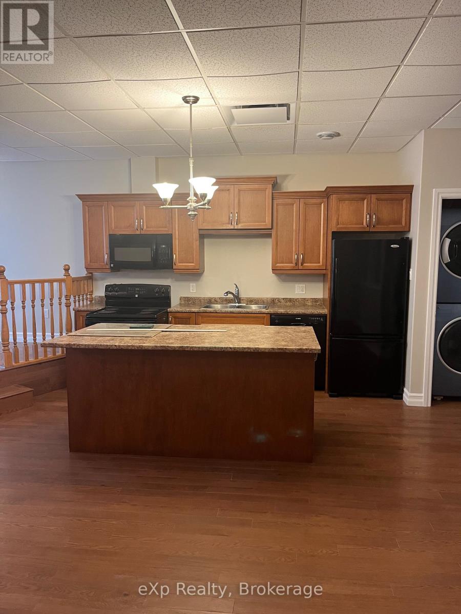 A kitchen with wooden cabinets and a black refrigerator.