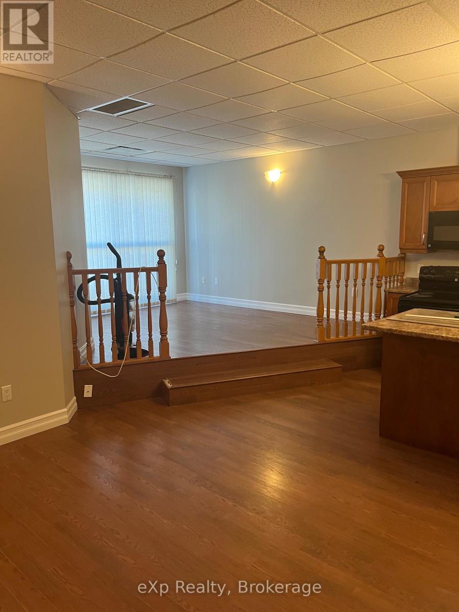 A room with wooden floors and a staircase leading to another room.