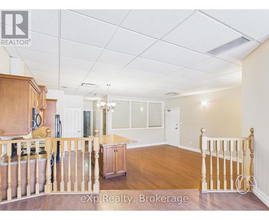 A room with wooden floors and a staircase leading to another room.