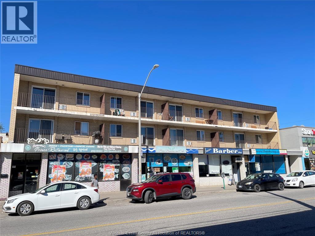 A street view of a multi-story building with cars parked in front.