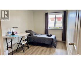 A bedroom with a bed, desk, and chair.